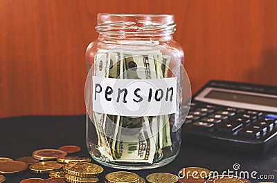 Coins in a glass jar and a calculator on black. Saving money. Pension concept. Stock Photo