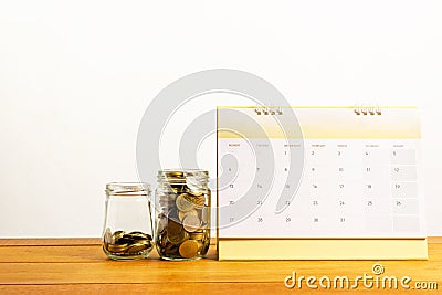 Coins in glass jar and calendar on wooden table for saving,accou Stock Photo