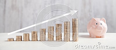 Coins, piggy bank on white table with a growth arrow Stock Photo