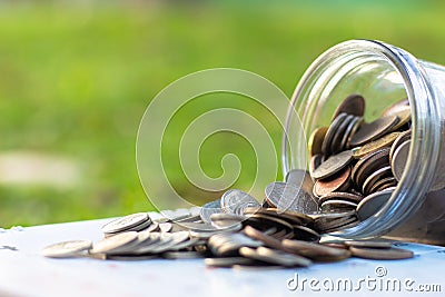 Coins spilling from a money glass jar Stock Photo