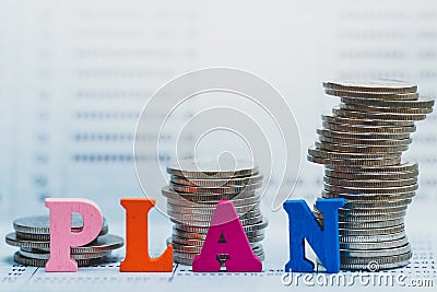 Coins stacking and Wooden Blocks with the text PLAN on bank passbook. Stock Photo