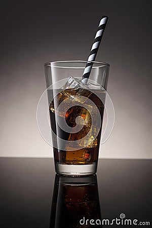Cola with rum and ice in a glass with a striped tubule. Stock Photo