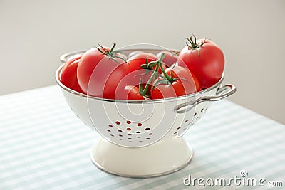 Colander with delicious tomatoes on table Stock Photo