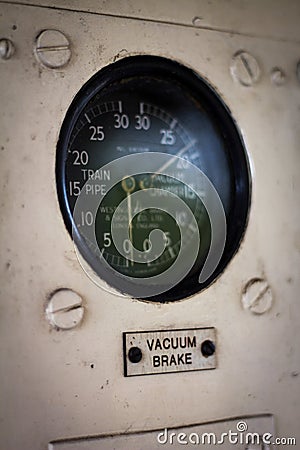 Vintage railway vacuum brake guage in coltrol panel. Black guage dial with white writing on a cream panel Editorial Stock Photo