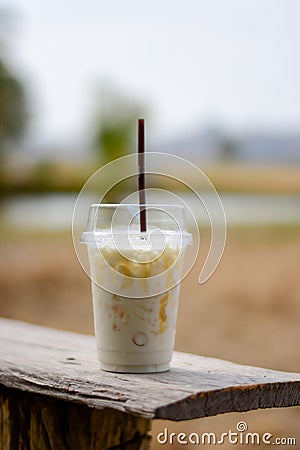 Cold caramel milk in clear plastic glasses on glass table Stock Photo