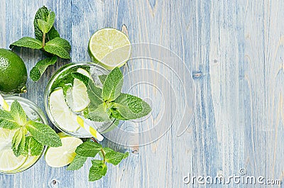 Cold detox summer mineral water with lime, mint, ice, straw on soft blue wood background as decorative border, top view. Stock Photo