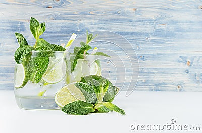 Cold detox summer mineral water with lime, mint, ice, straw on soft blue wood background, copy space. Stock Photo