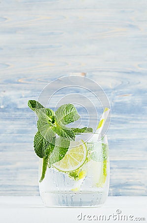 Cold detox summer mineral water with lime, mint, ice, straw on soft blue wood background, copy space. Stock Photo