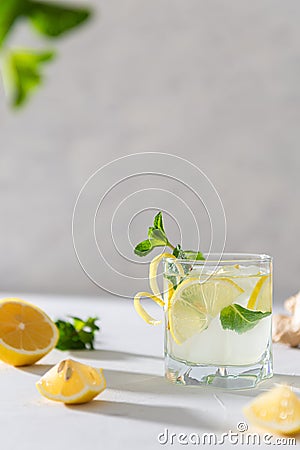 Cold detox water with lemon. Glass with lemonade or mojito cocktail with lemon, ginger and mint, cold refreshing drink with ice on Stock Photo