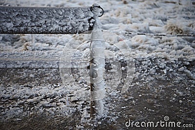 Cold winter photography image of outdoor bench or seat covered in wind swept frozen water and ice with snow background Stock Photo