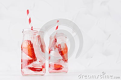 Cold fresh fruit beverage of ripe strawberry with ice, soda water, bubbles, funny striped straw on simple soft bright white. Stock Photo