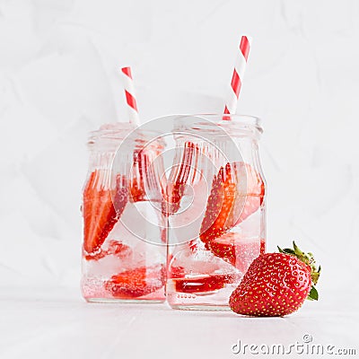 Cold fresh fruit beverage of ripe strawberry with ice, soda water, bubbles, funny striped straw on simple soft bright white wood. Stock Photo