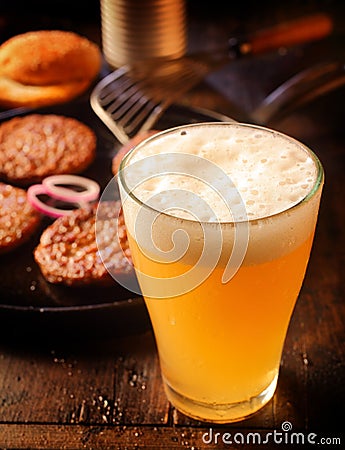 Cold glass of frothy beer with burger patties Stock Photo