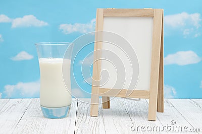 Cold glass of milk with chalkboard on weathered wood with clear sky Stock Photo