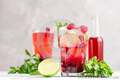 Cold pink non-alcohol cocktail with raspberry, lime, mint and ice cubes on light grey concrete background Stock Photo