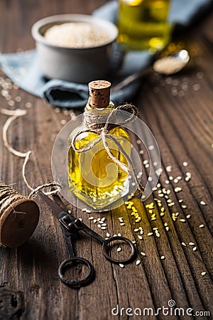 Cold pressed sesame oil in a glass bottle and seeds in a bowl Stock Photo