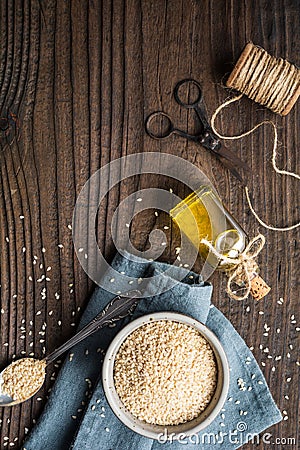 Cold pressed sesame oil in a glass bottle and seeds in a bowl Stock Photo