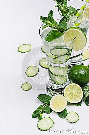 Cold spring drink with cucumber, pieces of lime, fresh leaves mint and ice cubes on soft white background, closeup. Stock Photo