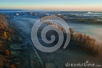 Autumn yellow trees and foggy blue valley. Sunrise. City at the background. Fall mood warm and cold colors Stock Photo