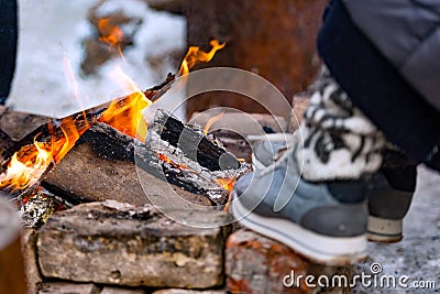 In the cold winter day a person heats feet to the fire. Stock Photo