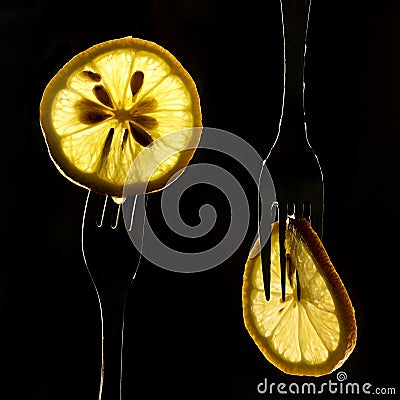 Collage of three slices of lemons on the fork on dark black background. silhouette of a fork in the back light. Drops of juice Stock Photo