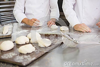Colleagues kneading uncooked dough on worktop Stock Photo