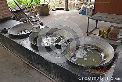 Collected coconut tree sap heated in large woks to evaporate the moisture content of the sap Stock Photo