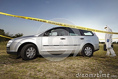 Collecting of evidences and traces by criminologist around car Stock Photo