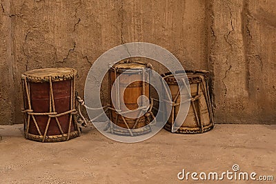 Collection of ancient vintage wooden drums near clay walls in heritage village .Percussion oriental musical instruments Stock Photo