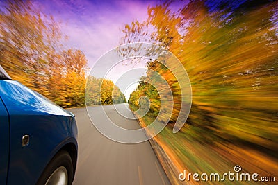 A car on curvy autumn forest road, with motion blur from its speed Stock Photo