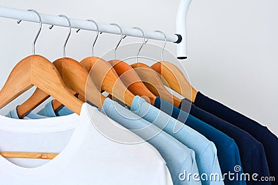 Collection shade of blue tone color t-shirts hanging on wooden clothes hanger in closet Stock Photo