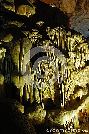 Spotlit stalactites in a cave forming grotesque shapes. Stock Photo
