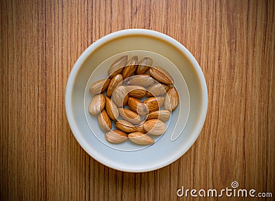 Collection Wet soaked almonds in a plastic bowl kept on a wooden base Stock Photo