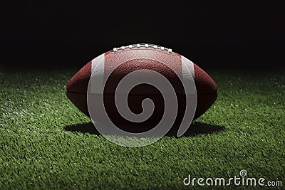 College football on grass field at night with spot lighting Stock Photo