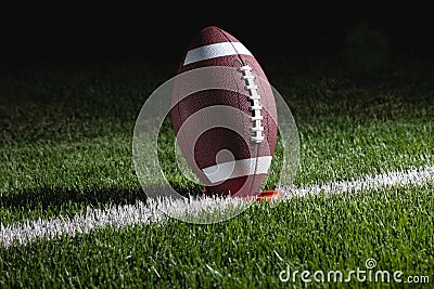 College football on tee at night ready for kick of Stock Photo