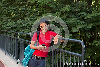 College student with a backpack looking at her cell phone Stock Photo