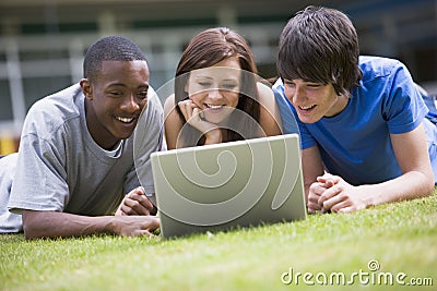 College students using laptop on campus lawn Stock Photo