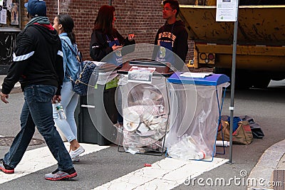 College students were seen at a street fair making sure that the people put their trash in the correct trash receptacles for Editorial Stock Photo
