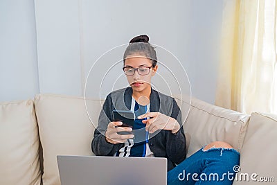 College woman on the couch checking her cell phone Stock Photo