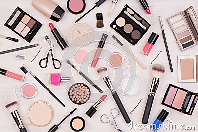 Makeup cosmetics such as eyeshadows, lipstick, mascara and makeup accessories on white, wooden background, top view Stock Photo