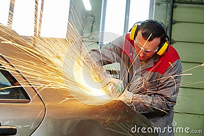 Collision repairs service. mechanic grinding car body by grinder Stock Photo