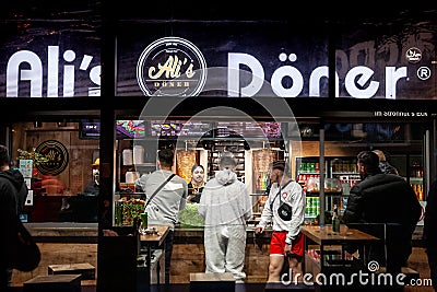 COLOGNE, GERMANY - NOVEMBER 11, 2022: Selective blur on youngsters with Cologne Carnival costume in a kebab fast food restaurant Editorial Stock Photo