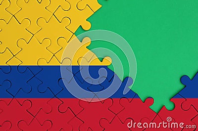 Colombia flag is depicted on a completed jigsaw puzzle with free green copy space on the right side Stock Photo