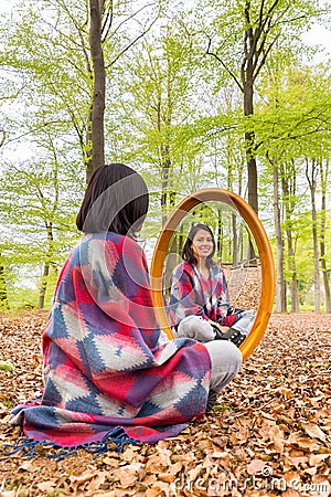 Woman sits in forest with mirror during spring Stock Photo