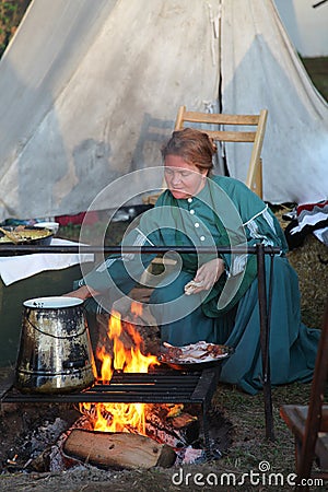 Colonial woman cooking over a fire Editorial Stock Photo