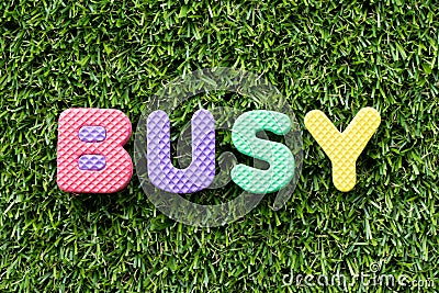 Color alphabet letter in word busy on green grass background Stock Photo