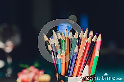 Color pencils in yellow polka dot paper glass over retro green background. Stock Photo