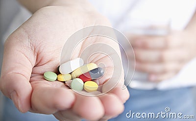 Color pill and a glass of water in female hands. health concept. Stock Photo