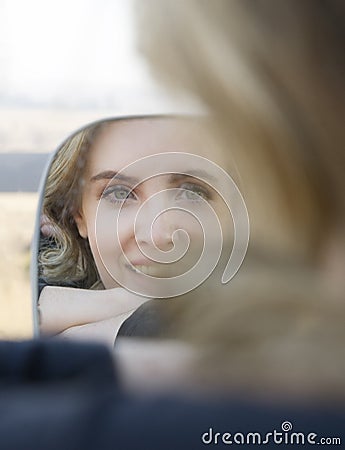 Porrtrait of smiling blonde woman in car side mirror Stock Photo