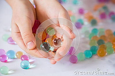 Colored balls of hydrogel in child`s palms. Sensory experiences Stock Photo